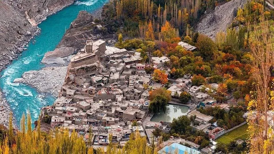 The old stacked settlement of Altit above the turquoise Hunza River, framed by autumn poplars and orchards