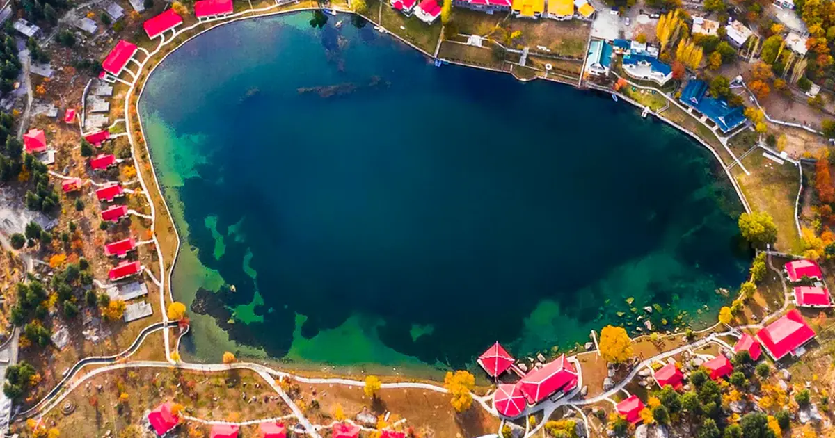 Aerial view of Shangrila Resort on Lower Kachura Lake near Skardu, ringed by red-roofed cottages and autumn trees, Gilgit-Baltistan