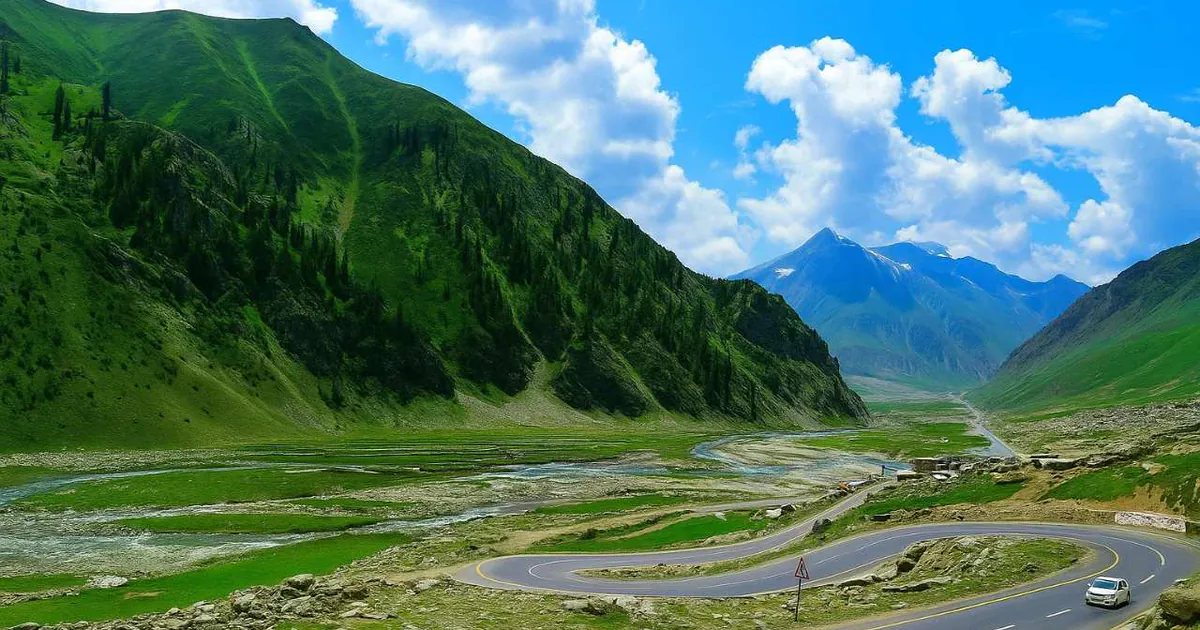 The winding road through the green Kaghan Valley below snow-capped peaks on the way to Babusar Top, Pakistan