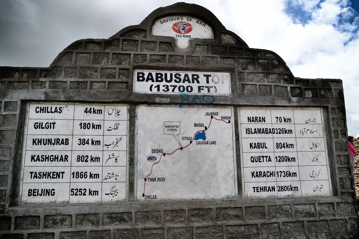 Stone milestone and map at Babusar Top (13,700 ft) listing road distances to Chilas, Gilgit, Naran and Islamabad
