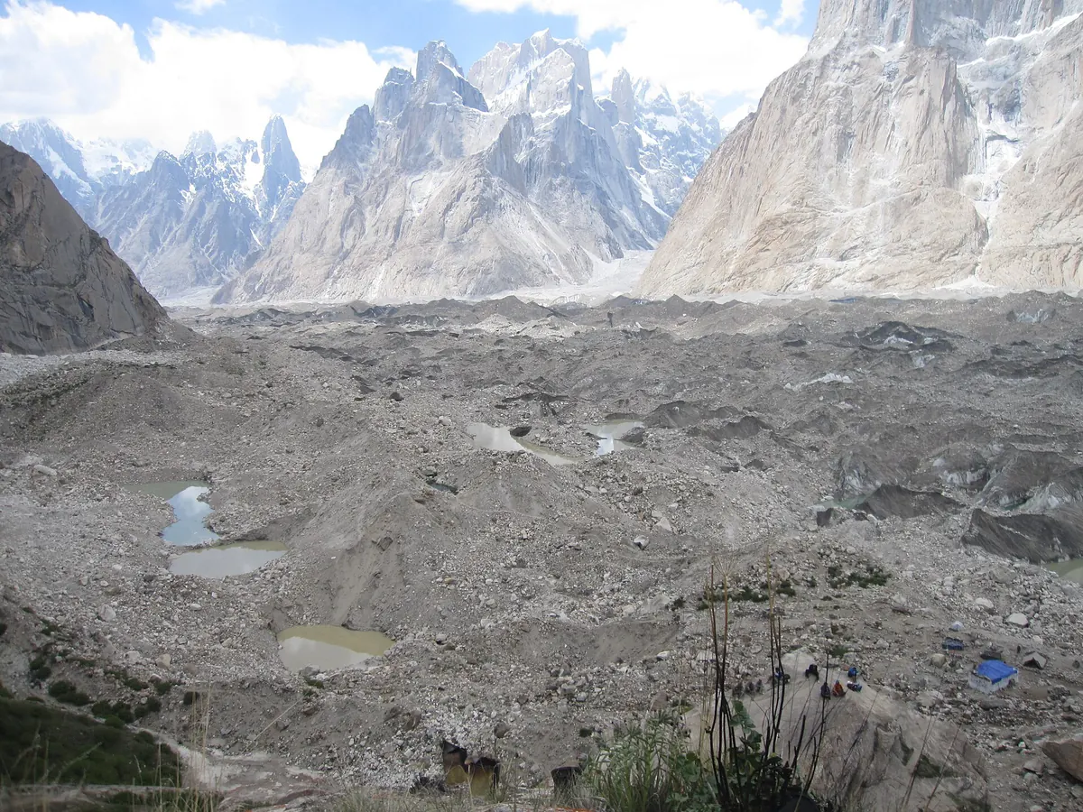 Der mit Geröll bedeckte Baltoro-Gletscher vom Lagerplatz Urdukas aus, dahinter Granittürme, K2-Basislager-Trek, Karakorum, Pakistan