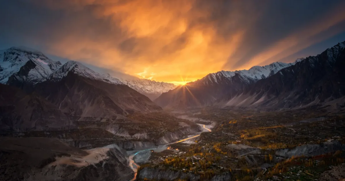 La Valle di Hunza al tramonto con le vette innevate del Karakorum che brillano sopra la valle verdeggiante