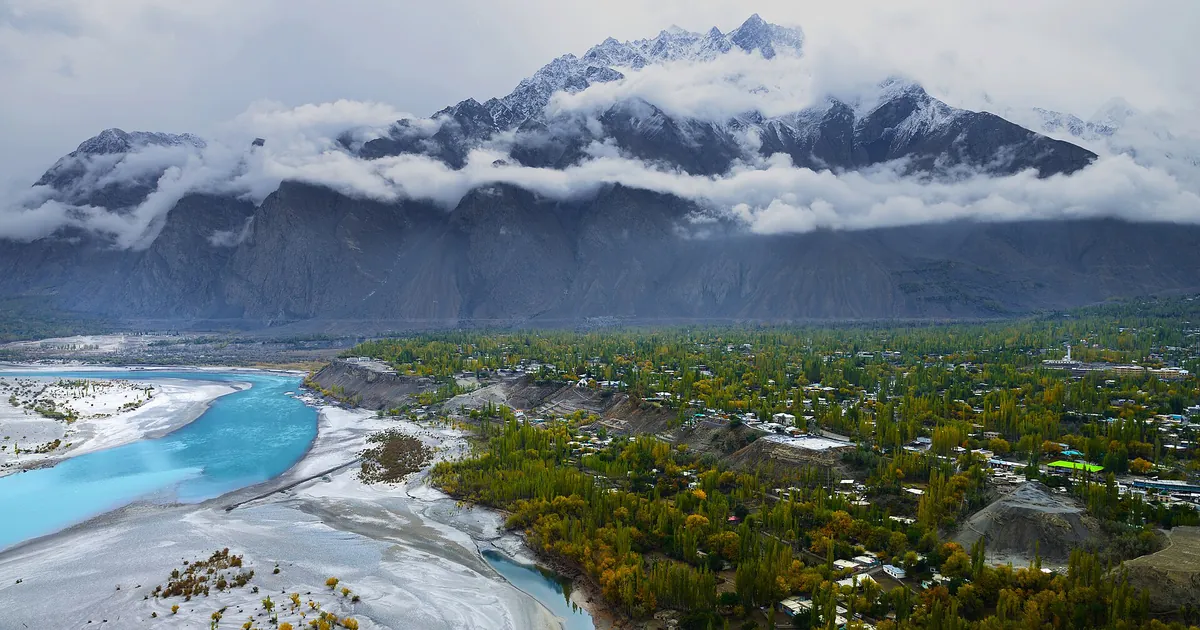 Autumn view over Skardu town in Baltistan, with golden poplars, the braided Indus river and snow-dusted Karakoram peaks under cloud