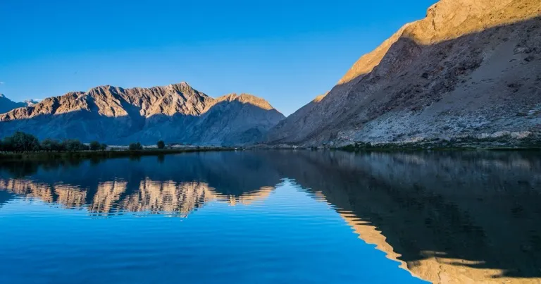 Blind Lake (Zharba Tso) near Skardu at sunrise, arid Shigar valley ridges reflected in still blue water, Pakistan