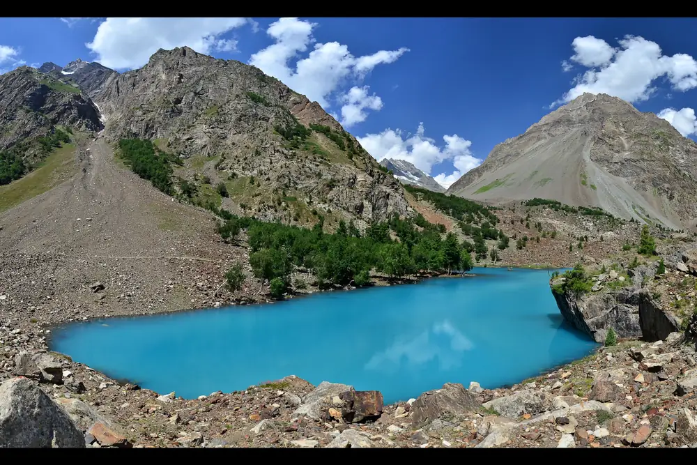 Hồ Blue Lake màu ngọc lam (Bashkiri II) ở thung lũng Naltar giữa những tảng đá xám, cây thông và sườn núi đá