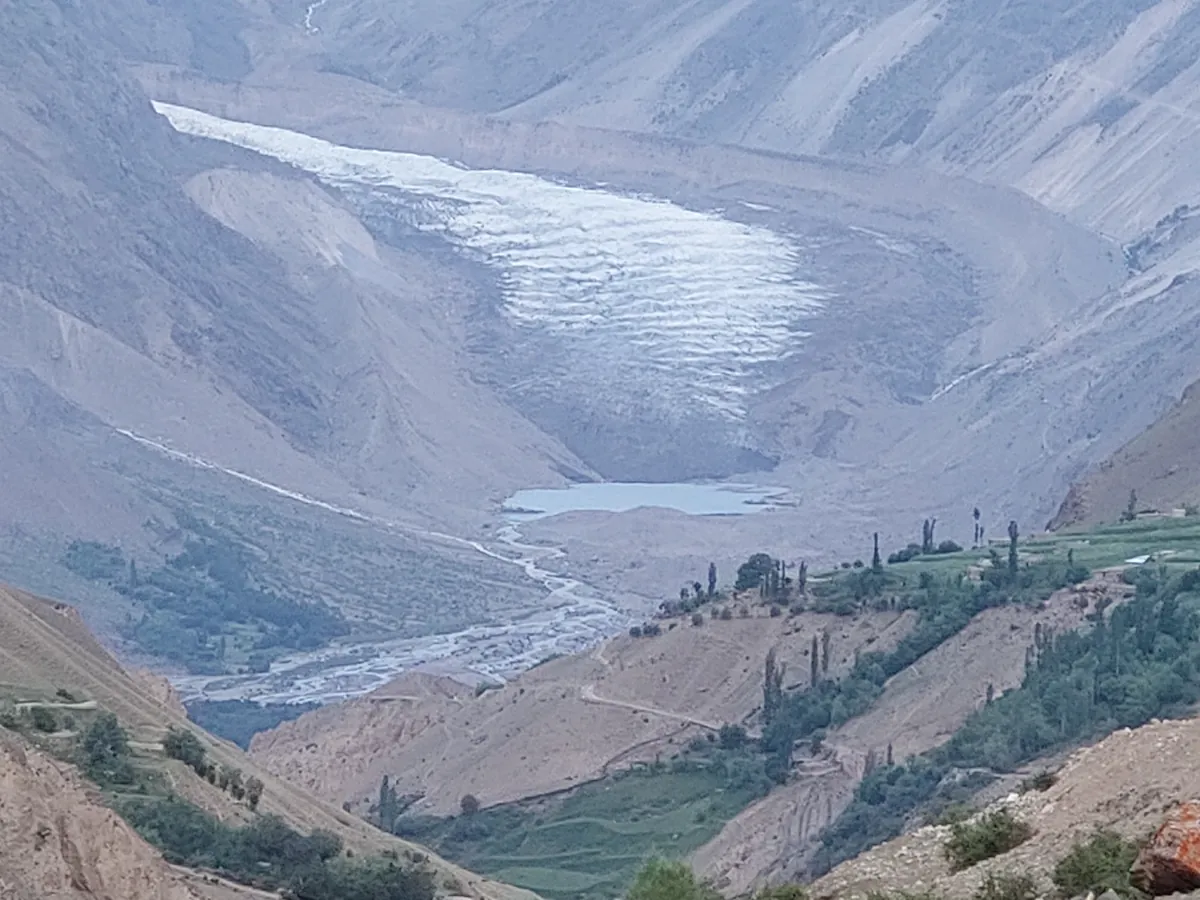 Darkot glacier and its meltwater lake above the green fields and poplars of Darkot village at the head of Yasin Valley, Gilgit-Baltistan, Pakistan