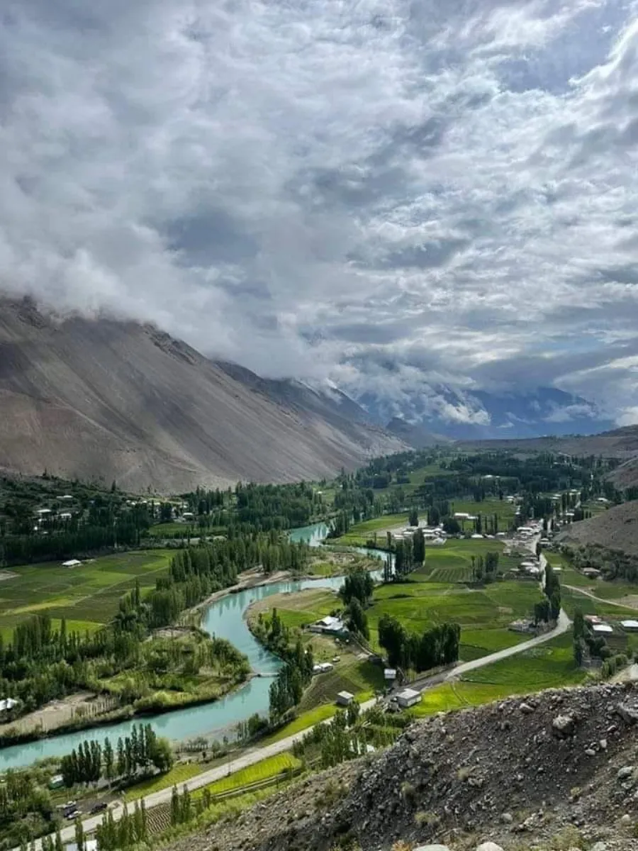 Der Ghizer-Fluss teilt sich in verzweigte türkisfarbene Arme über dem grünen Talboden des Phandar-Tals in Gilgit-Baltistan