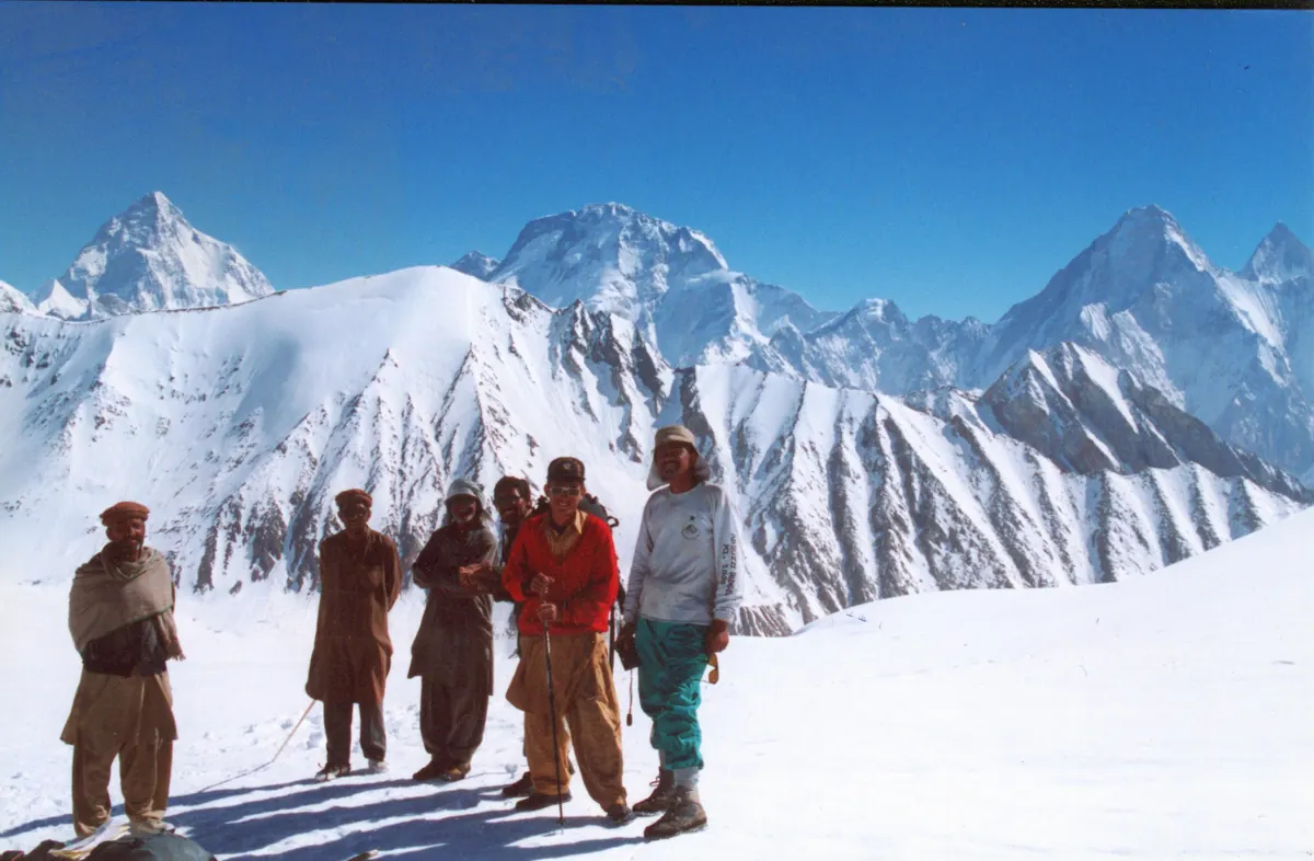 Träger auf der Passhöhe des Gondogoro La, im Norden K2, Broad Peak und die Gasherbrums am Horizont, Karakorum, Pakistan