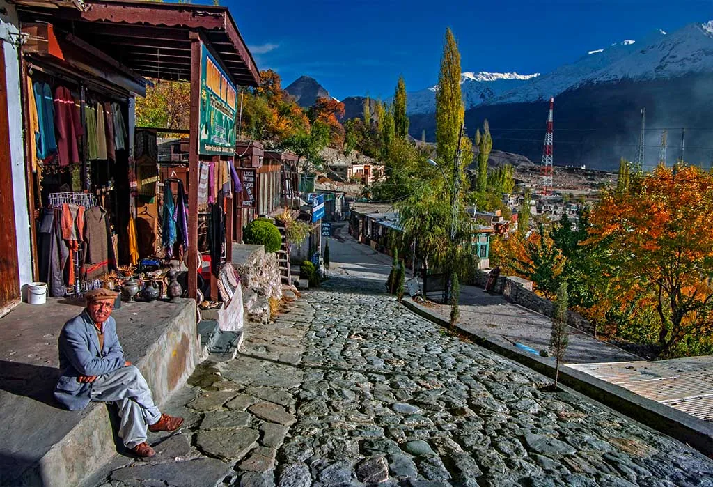 Antica via del bazar in ciottoli a Karimabad, Hunza, con pioppi autunnali e le vette innevate del Karakorum