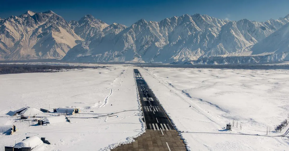 Snow-covered runway at Skardu International Airport seen from the air, with the Karakoram mountains rising behind the Indus valley