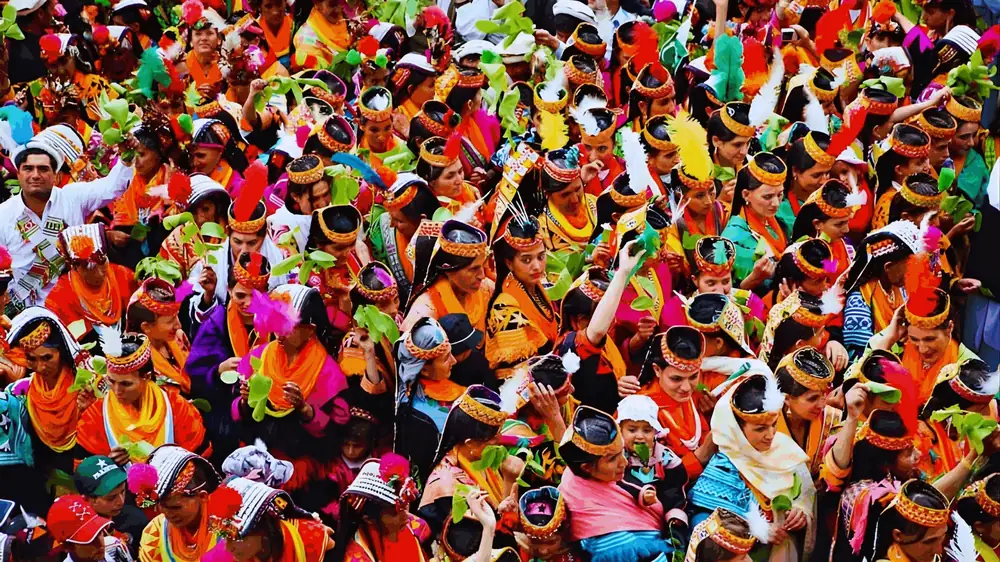 A crowd of Kalash women in orange headdresses and scarves waving walnut leaves at the Chilam Joshi dance in the Kalash valleys