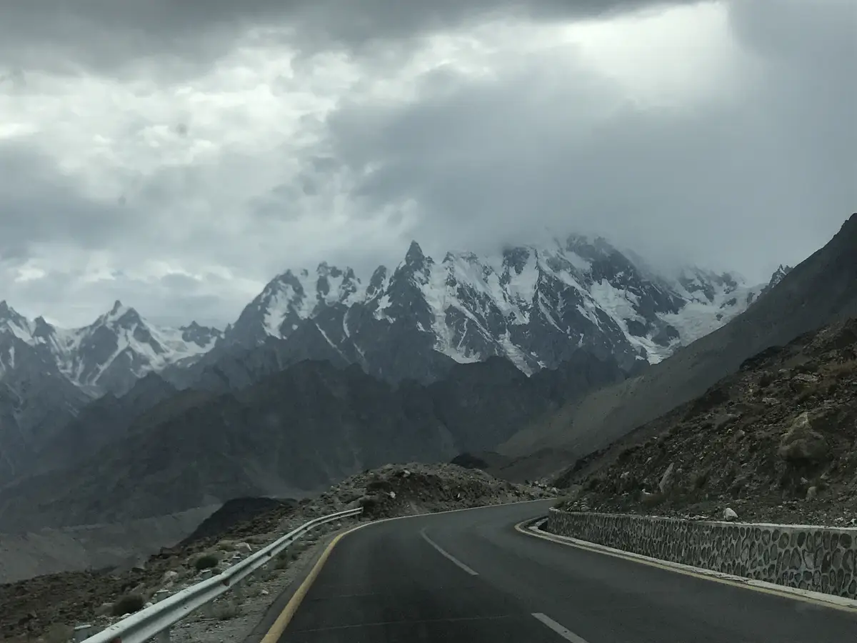 La Karakoram Highway asfaltata che curva sotto le Passu Cones innevate, alta valle di Hunza, Gilgit-Baltistan, Pakistan