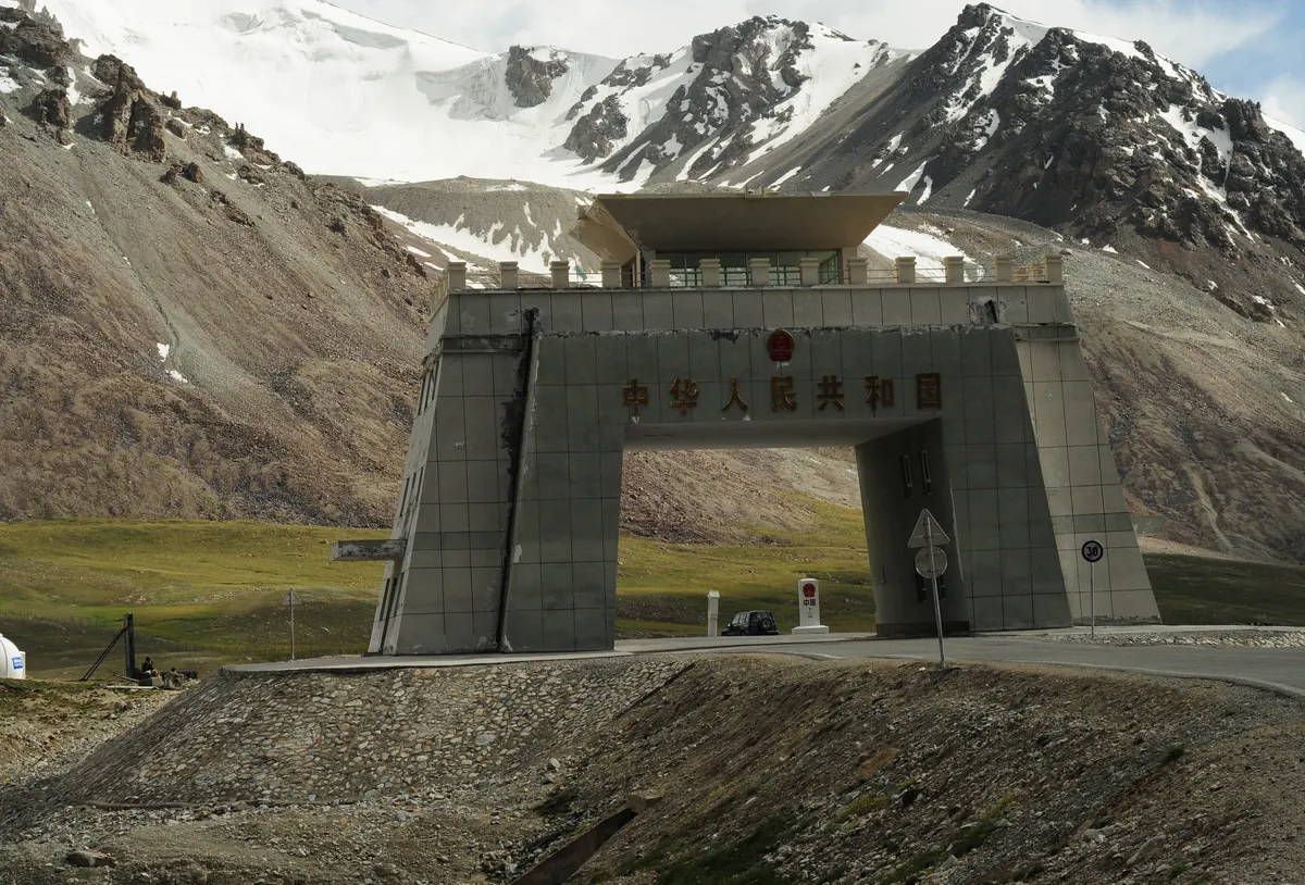 Grenztor auf der Passhöhe des Khunjerab-Passes am Karakorum Highway, mit Schneegipfeln an der Grenze zu China