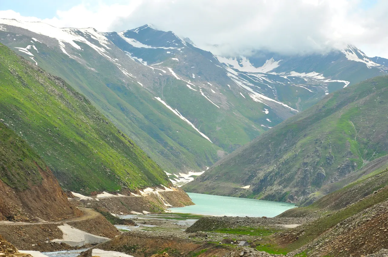 The turquoise Lulusar Lake below snow-streaked green mountains on the Naran to Babusar road, Kaghan Valley, Pakistan