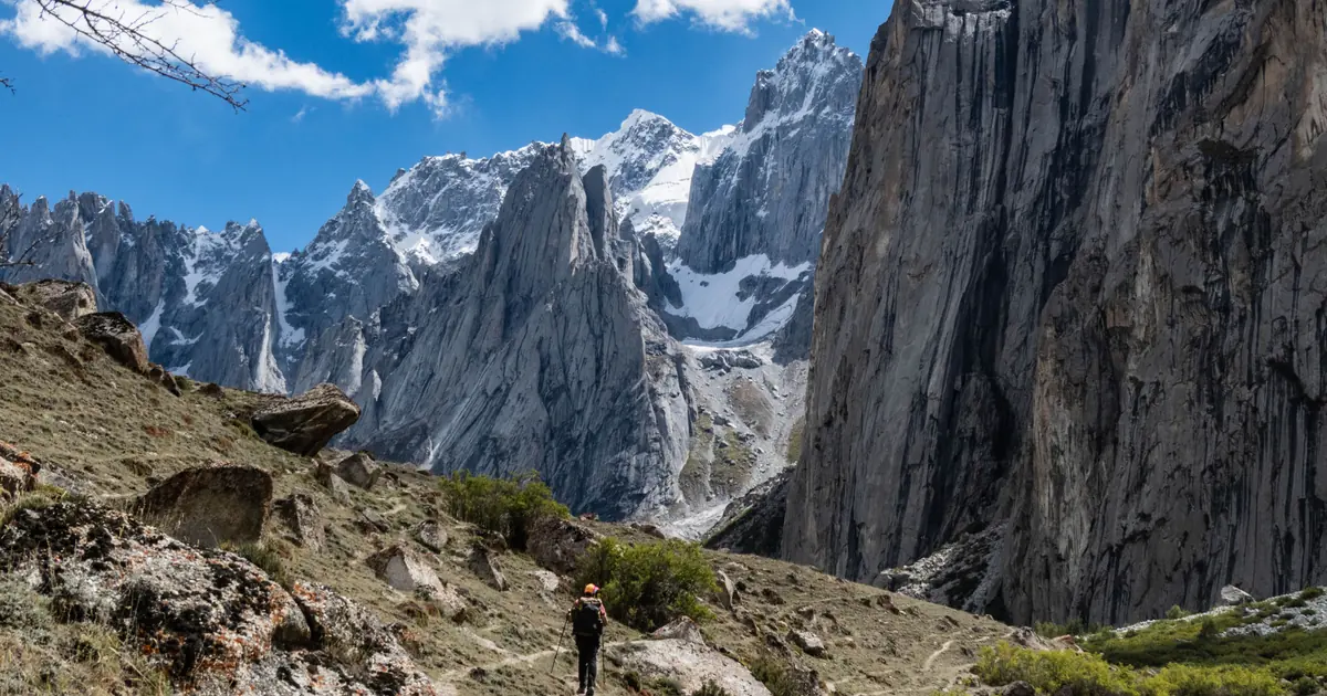 A trekker on the trail into Nangma Valley, Baltistan, beneath sheer granite walls and snow-capped Karakoram peaks