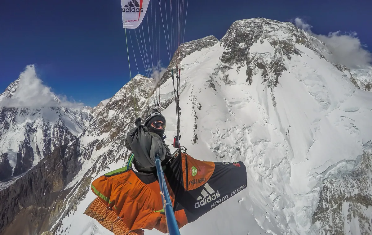 Gleitschirmpilot fliegt an der verschneiten Flanke des Broad Peak im Karakorum vorbei, hoch über dem Baltoro-Gletscher
