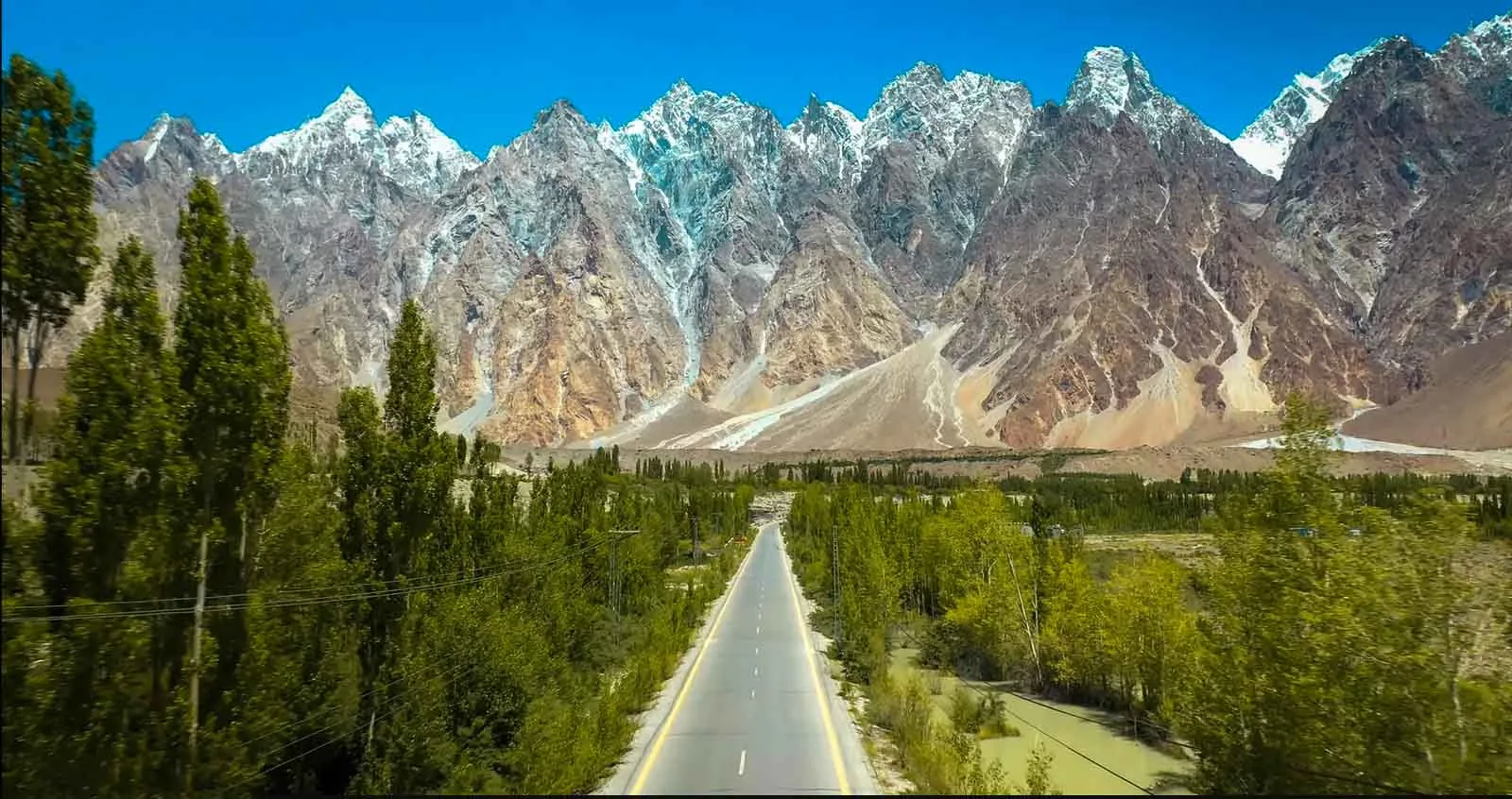 I frastagliati Passu Cones (Tupopdan, 6.106 m) che si ergono sopra la Karakoram Highway e i pioppi verdi vicino al villaggio di Passu, Hunza