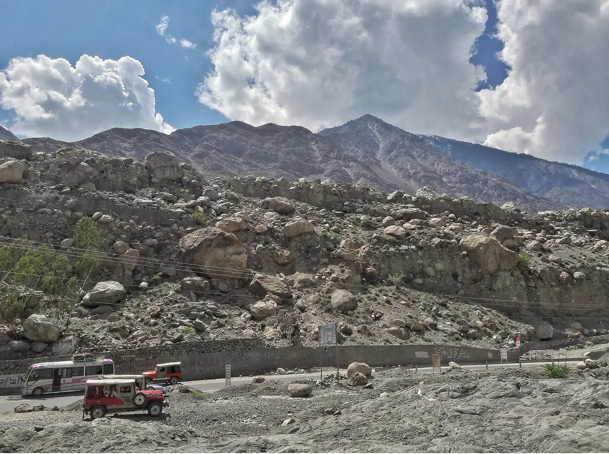Jeeps und ein Kleinbus am Parkplatz der Raikot-Brücke, dem Beginn der Piste zu den Fairy Meadows, unter einem felsigen Hang voller Blöcke, Gilgit-Baltistan
