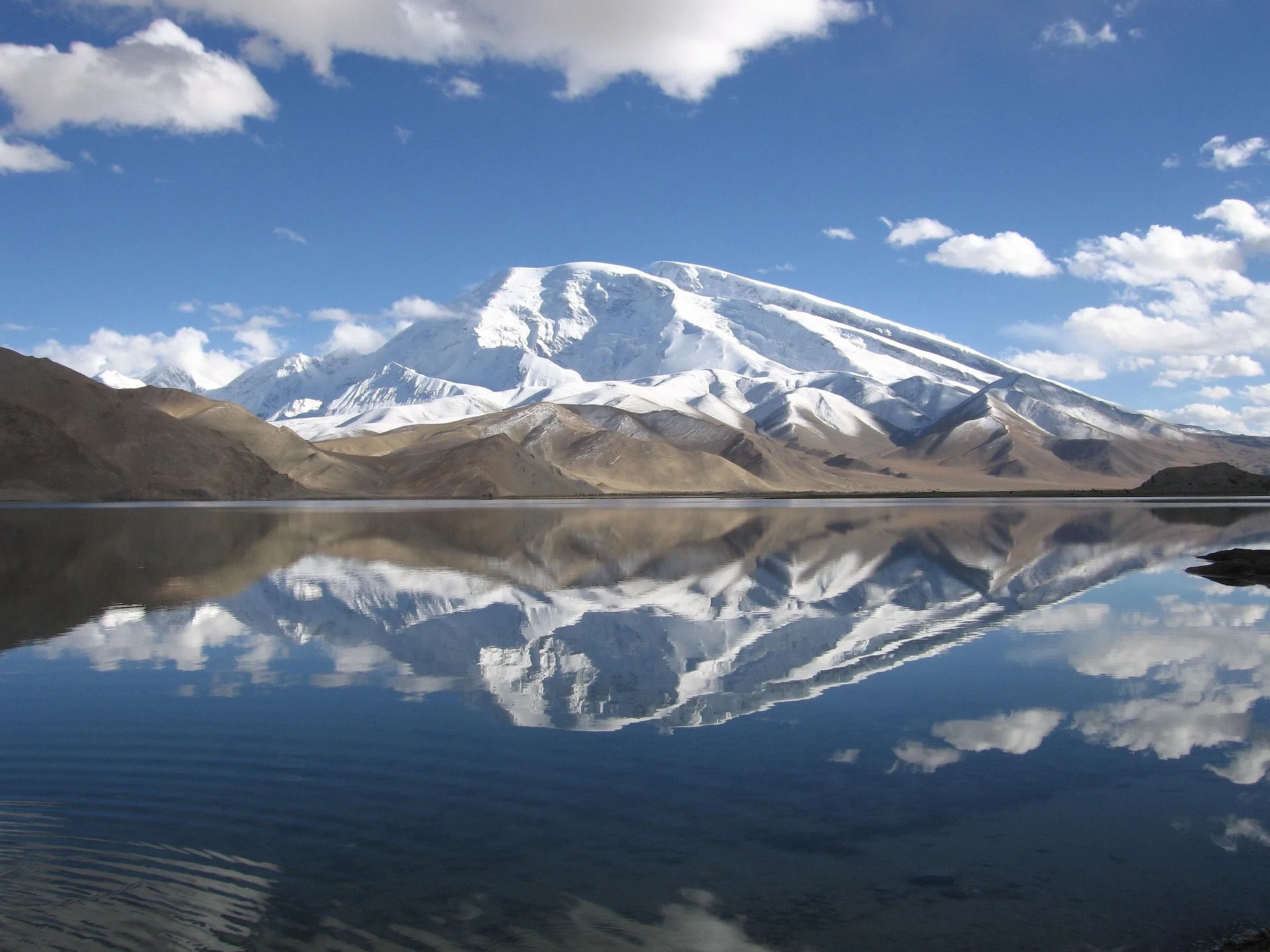 Muztagh Ata reflected in Karakul Lake under blue sky