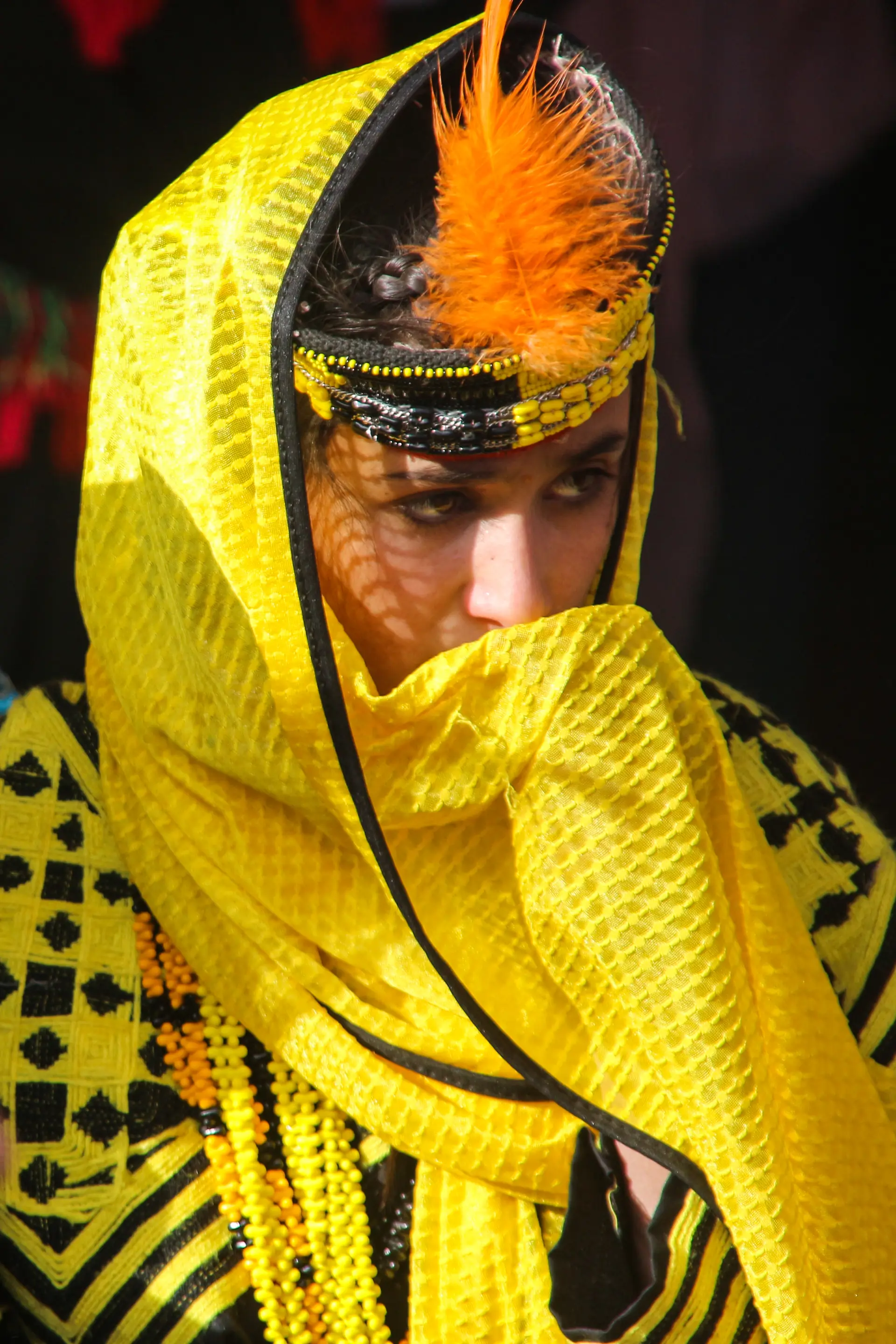 A Kalash girl in a feathered kupas cap and yellow veil at the Chilam Joshi spring festival, Chitral