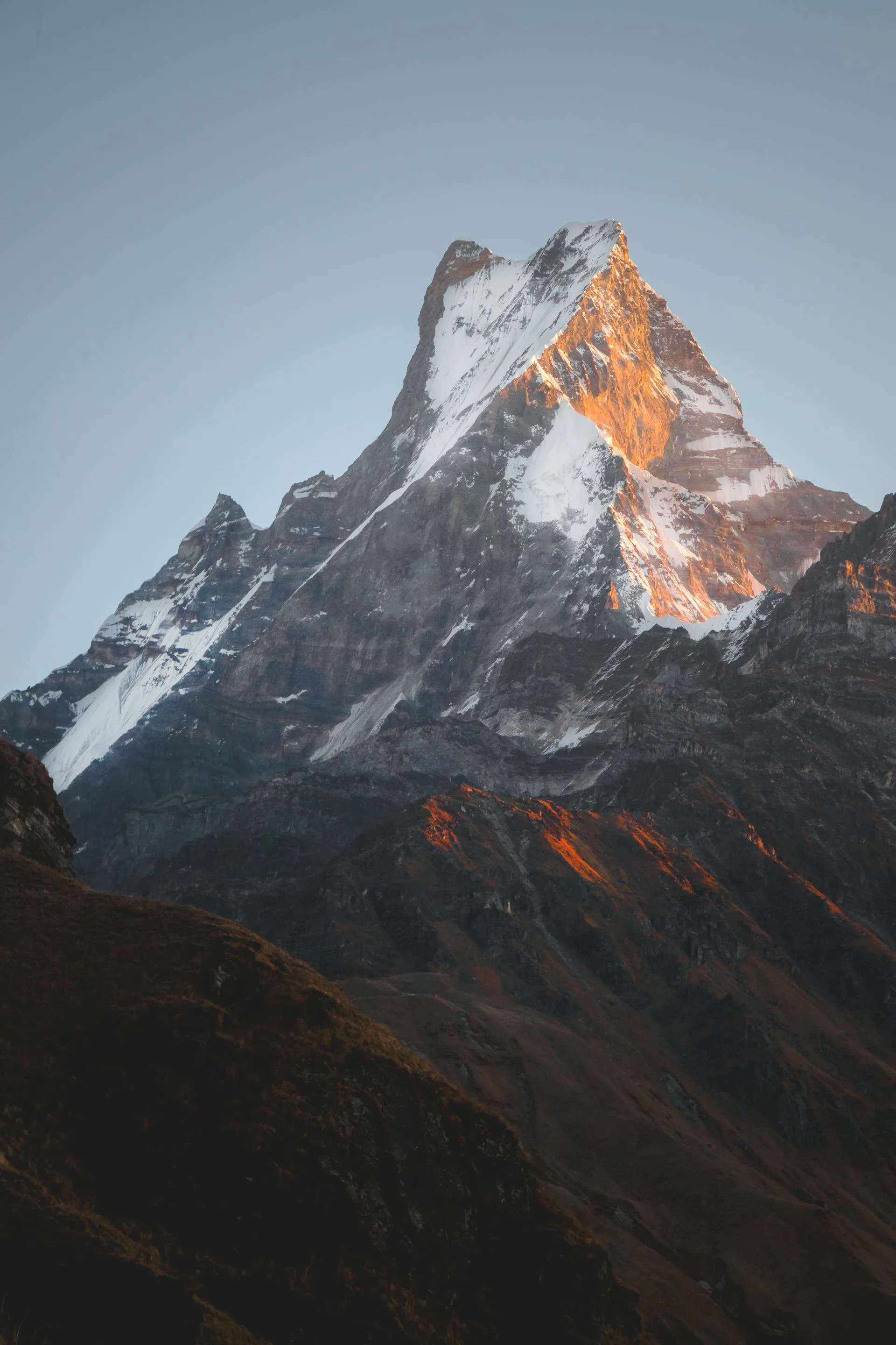 Golden sunrise light bathing a majestic snow-capped peak