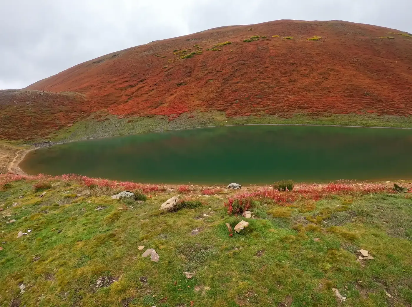Kacheli Lake below rust-red autumn slopes under low cloud, Kacheli Meadows, Nagar