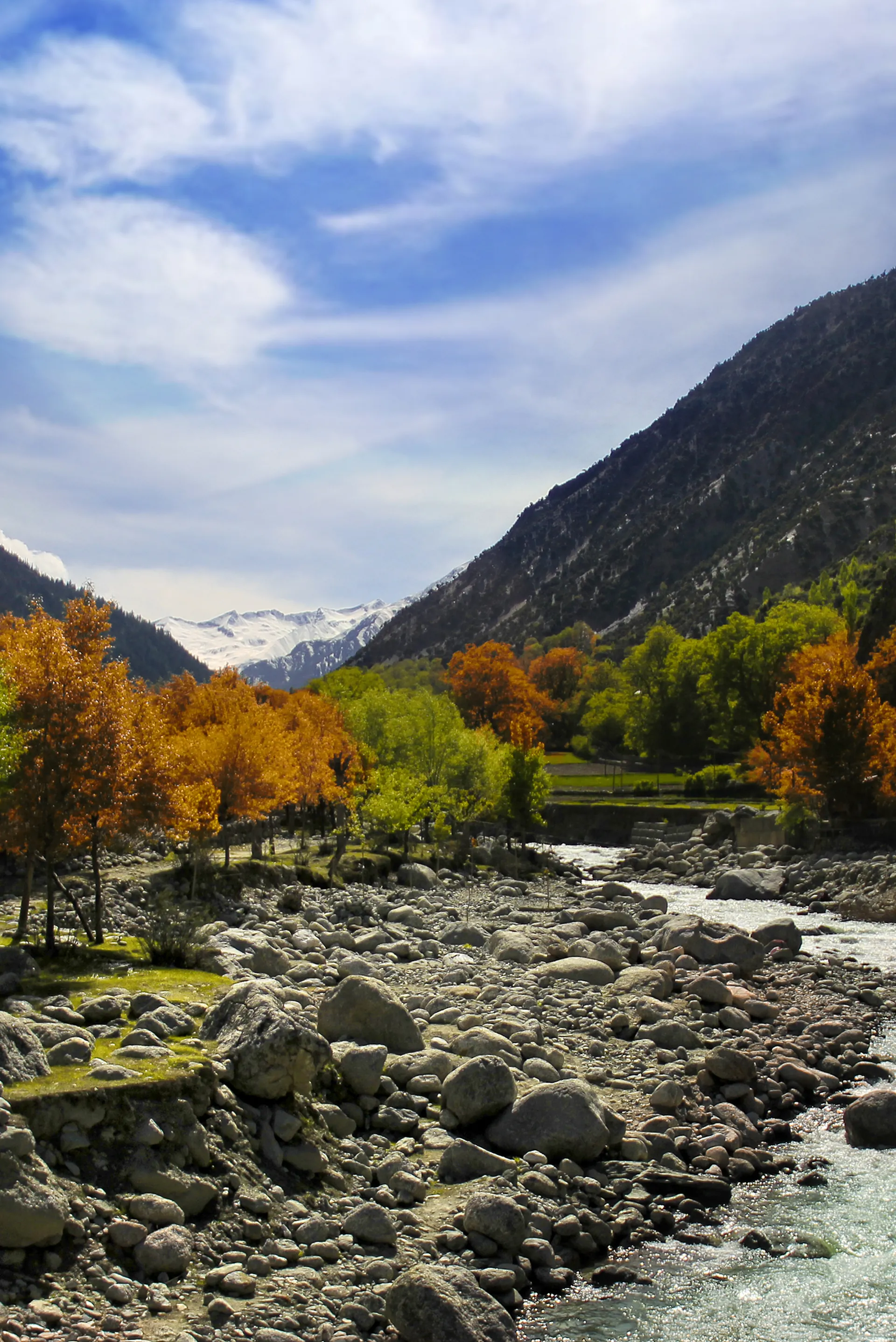 The Bumburet river flowing below the snow-capped Hindu Kush in the Kalash valleys, Chitral