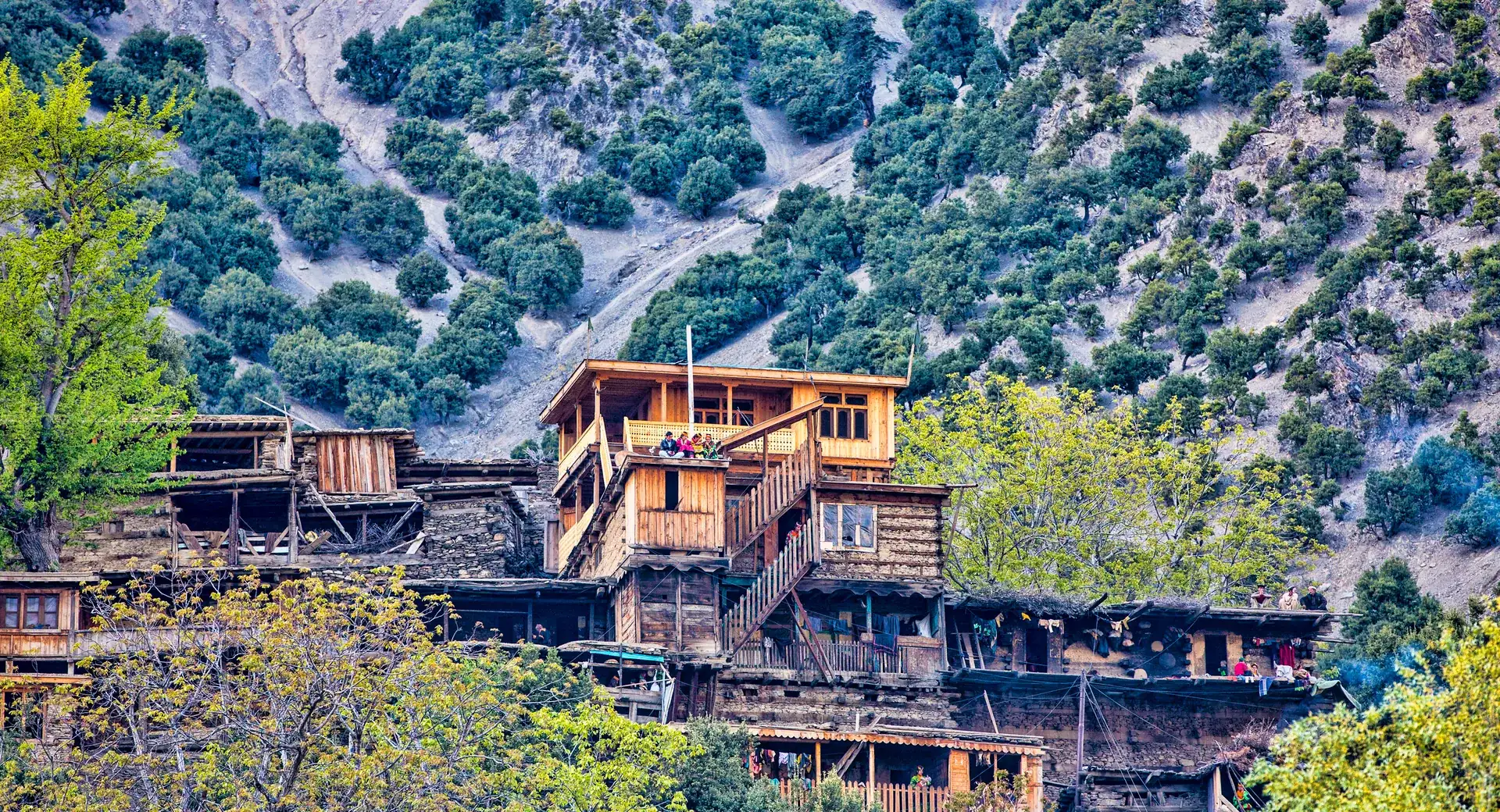 Traditional stacked timber Kalash houses beside the river