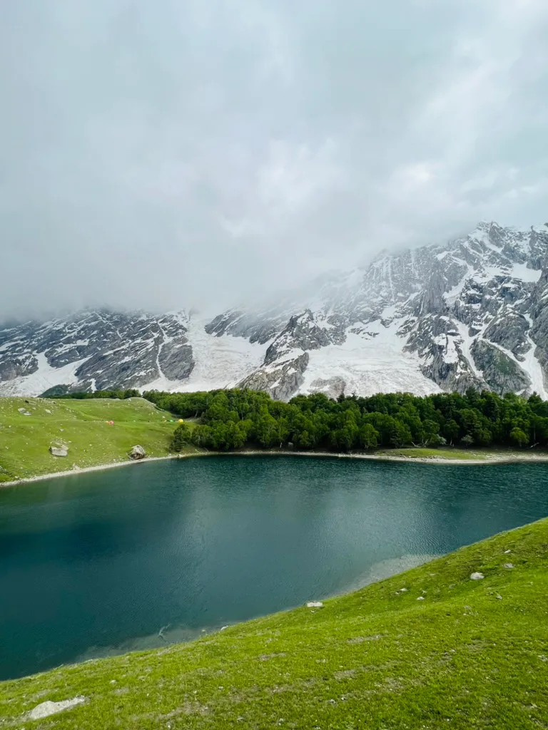 Kutwal Lake with camp tents on the meadow below the ice face of Haramosh