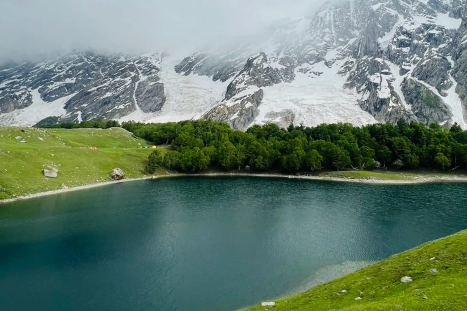 Kutwal Lake in the Haramosh Valley with camp tents on the meadow and the ice face of Haramosh Peak behind, Gilgit-Baltistan