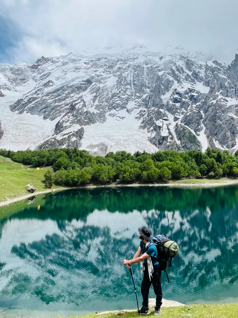 A trekker on the shore of Kutwal Lake looking across to Haramosh Peak