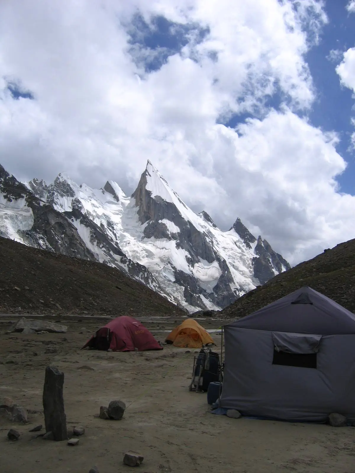 Tents at Laila Peak base camp with the snow spire rising between moraine walls