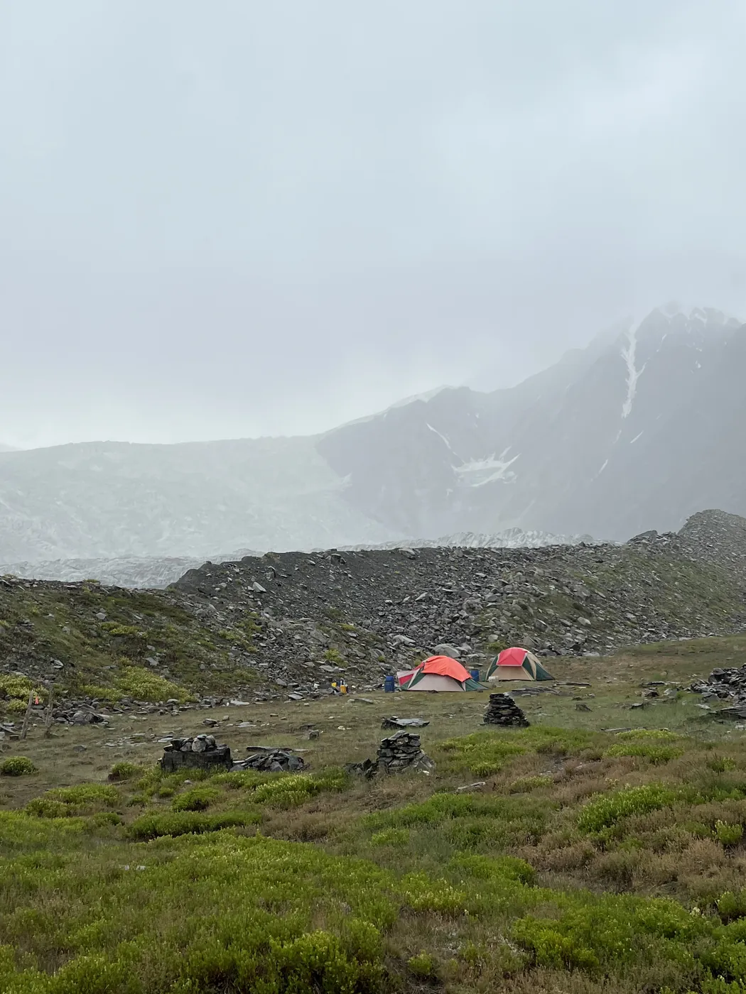 Tents pitched on the green meadow at Patundas in drifting cloud, Gojal, Upper Hunza