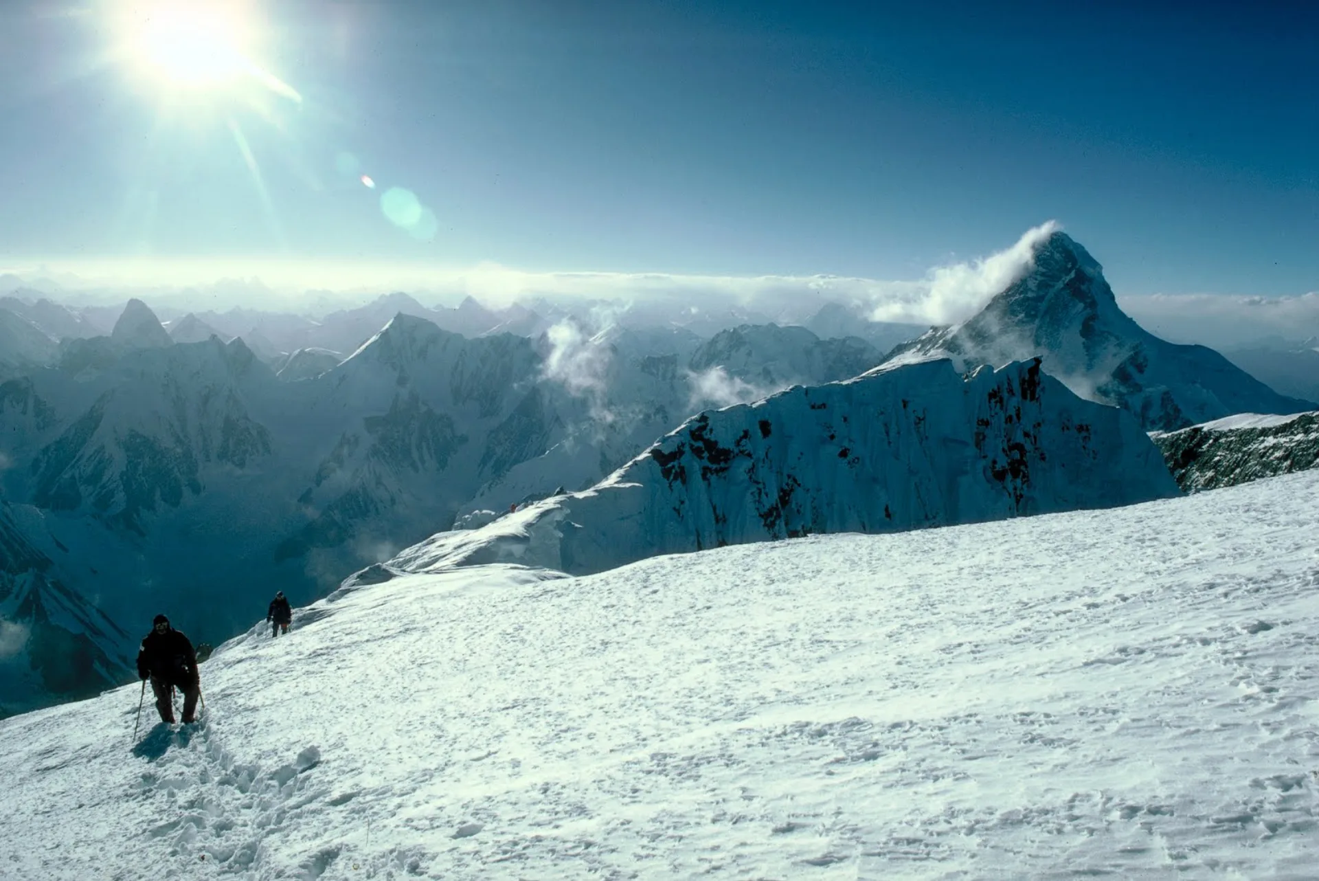 Climbers ascending Broad Peak snow slope with K2 summit visible in background Karakoram Pakistan